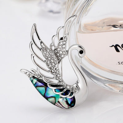 The Tropicana Ululani Brooch - A beautiful silver-toned zinc alloy swan brooch adorned with crystals and polished paua shell.