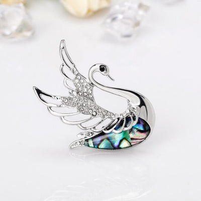The Tropicana Ululani Brooch - A beautiful silver-toned zinc alloy swan brooch adorned with crystals and polished paua shell.