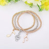 Whitney Stretch Bracelet Set - A set of simple beaded stretch bangles in beautiful gold, rose gold, or silver, with little charms that look like musical notes.