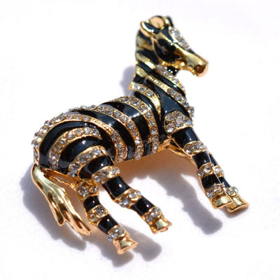 Zealous Zebra Brooch - A medium sized brooch shaped like a zebra standing still and looking forward, with a gold and black enamel background and studded with small crystals.