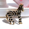 Zealous Zebra Brooch - A medium sized brooch shaped like a zebra standing still and looking forward, with a gold and black enamel background and studded with small crystals.