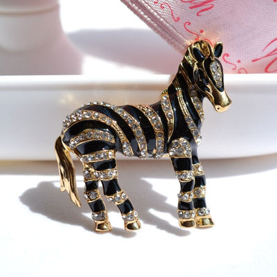 Zealous Zebra Brooch - A medium sized brooch shaped like a zebra standing still and looking forward, with a gold and black enamel background and studded with small crystals.