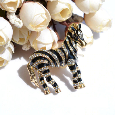 Zealous Zebra Brooch - A medium sized brooch shaped like a zebra standing still and looking forward, with a gold and black enamel background and studded with small crystals.