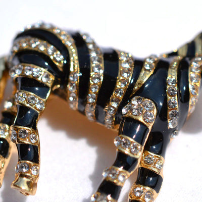 Zealous Zebra Brooch - A medium sized brooch shaped like a zebra standing still and looking forward, with a gold and black enamel background and studded with small crystals.