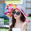 Heavenly Hibiscus Reversible Sunhat - A lovely, brightly-coloured large-brimmed sunhat with a solid colour on one side and a complimentary floral print on the other, which can be worn either way. It has a detachable scarf. This image shows a model wearing the Khaki colour, which is a light creamy brown.