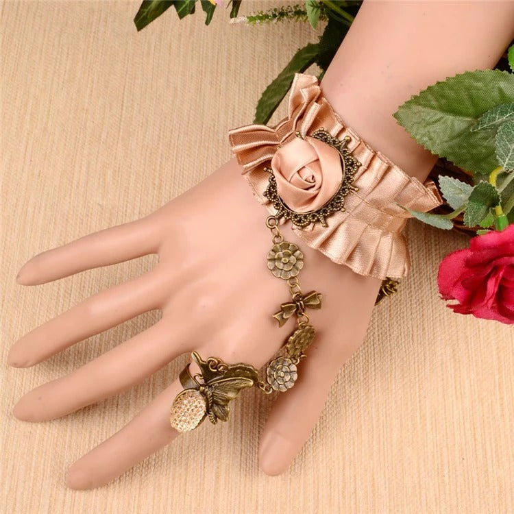 The Louisa Cuff - A lovely salmon-coloured cuff bracelet adorned with ribbons, metal hardware, and faux gems. 