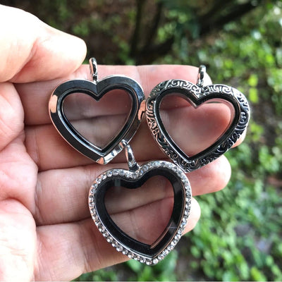 Kalliope Magnetic Floating Locket - A heart-shaped locket with glass panels in the front and back, allowing the user to place whatever they want on display in between. It is available in gold, gunmetal (dark silver) rose gold, or silver, and in either jewelled or etched/carved.