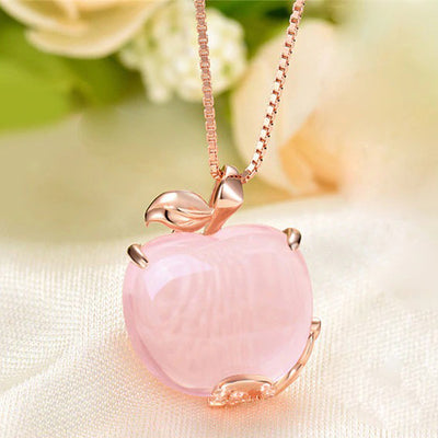 The Pomona Necklace - A lovely, luxurious-looking pink opal pendant shaped like an apple, with rose gold accents and a scattering of tiny quartz crystals.