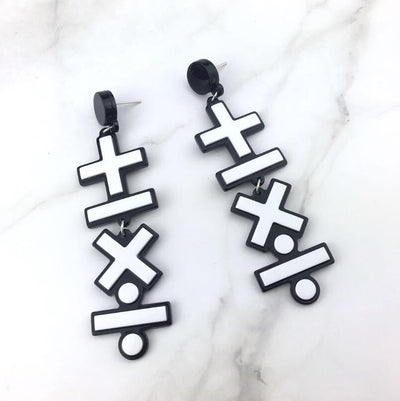 Retro Revival Mathematician Earrings - Long dangly earrings with mathematics symbols, plus, minus, times, and divide. They are white plastic with a black plastic background, to make it look like they have a cartoon-style outline.